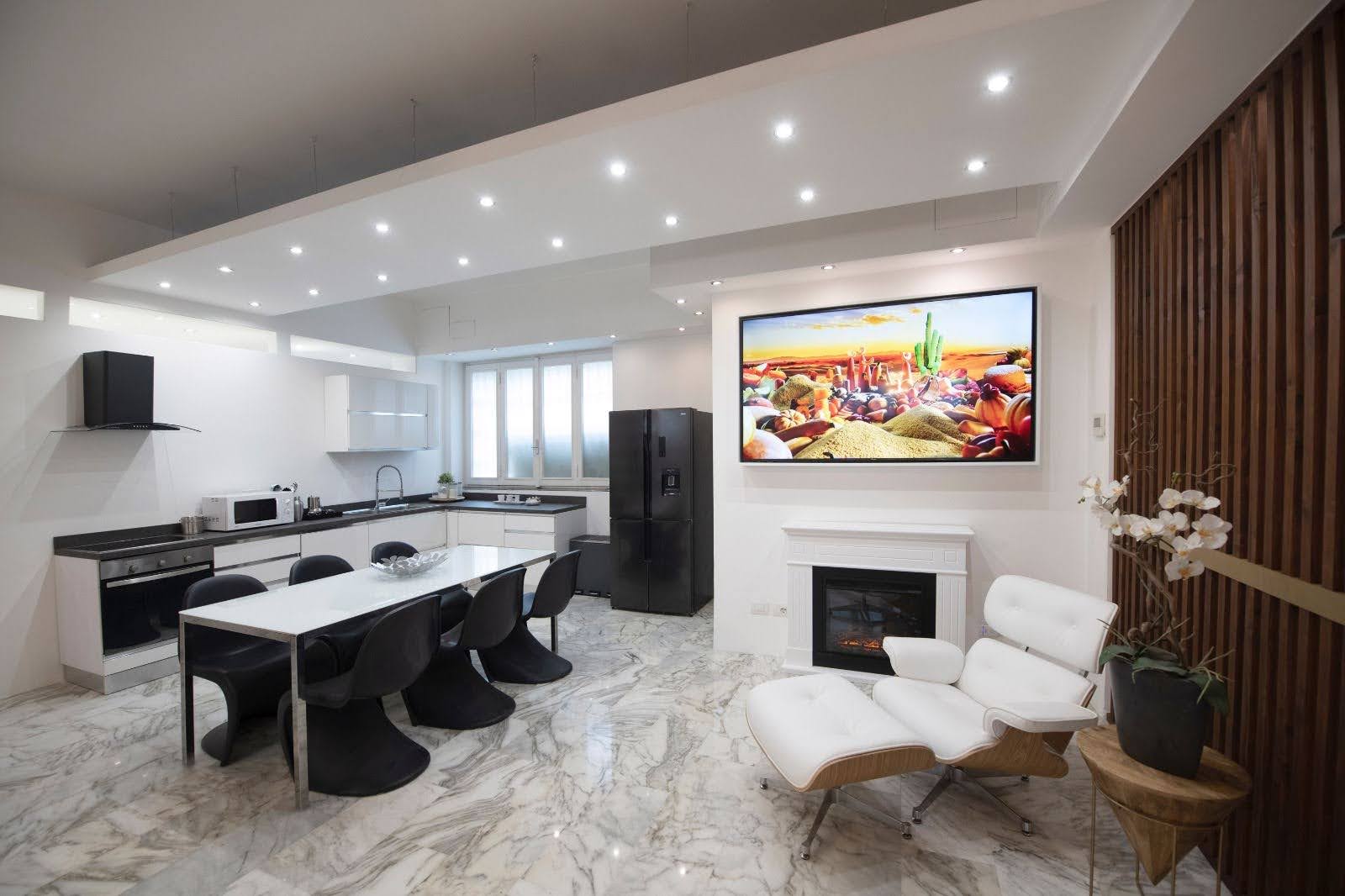 Kitchen and dining space in a Milan design apartment with fireplace, marble flooring and lounge chair
