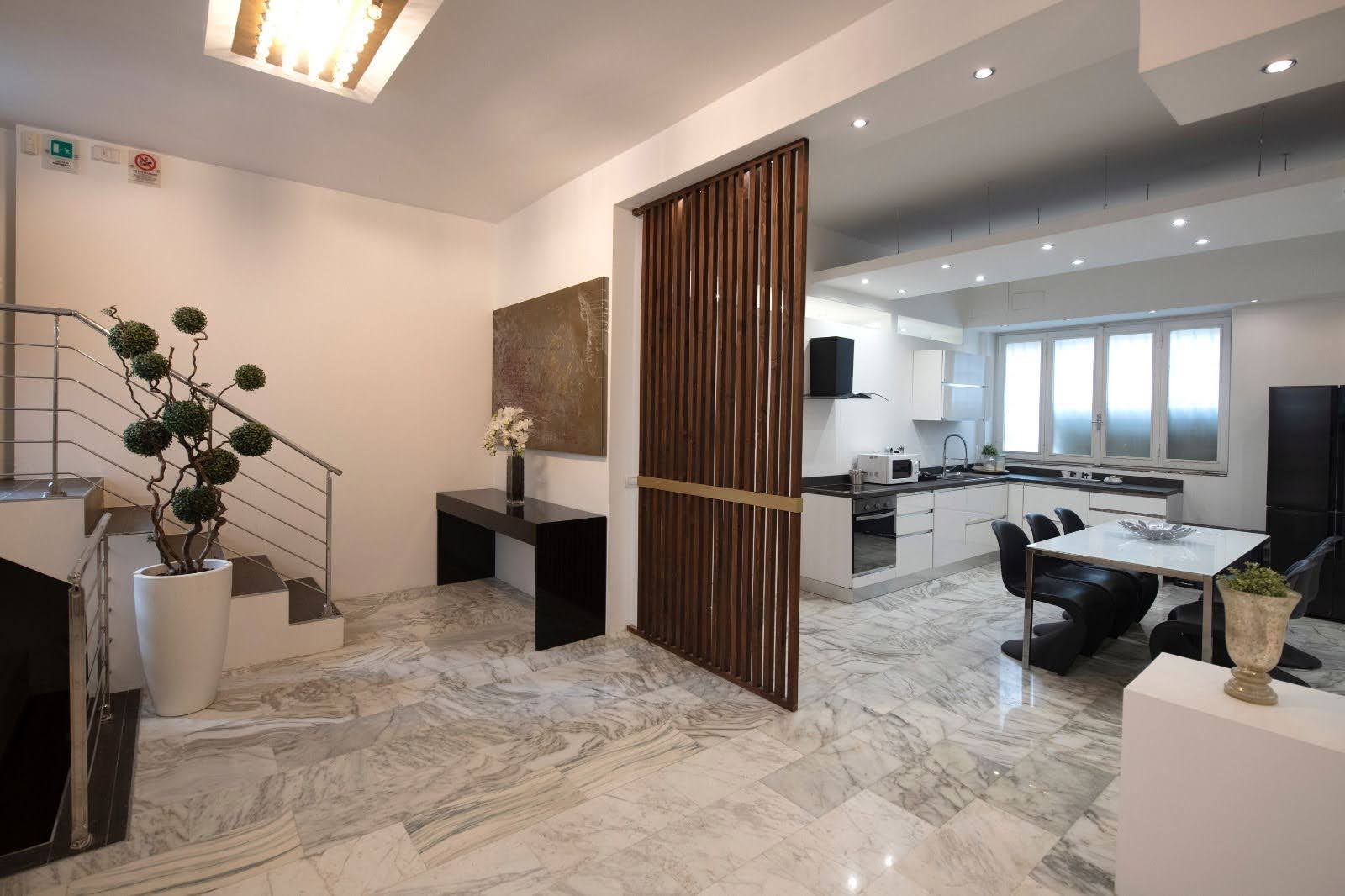 Open-plan design apartment in Milan with kitchen, dining area, marble flooring and walnut divider